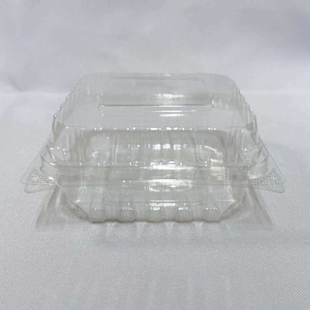 Envase cuadrado descartable de plástico transparente (PET) tipo estuche. Se presenta en dos imágenes: una con el envase completamente abierto exhibiendo su interior profundo y su tapa unida por bisagra, y otra mostrando el envase cerrado de frente, ambas sobre un fondo claro.