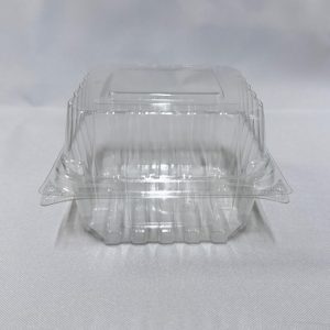 Envase cuadrado de plástico transparente (PET) tipo estuche, mostrado completamente abierto dejando ver su base profunda y su tapa alta unida por bisagra, sobre un fondo claro.