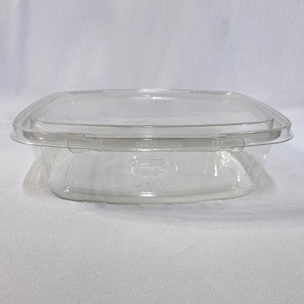 Envase rectangular descartable de plástico transparente (PET) tipo estuche de extra gran capacidad. Se presenta en dos imágenes: una mostrando el envase completamente abierto para apreciar su interior súper amplio y profundo con la tapa unida por bisagra, y otra del envase cerrado visto de frente donde resalta la pestaña del precinto de seguridad perimetral, ambas sobre un fondo claro.