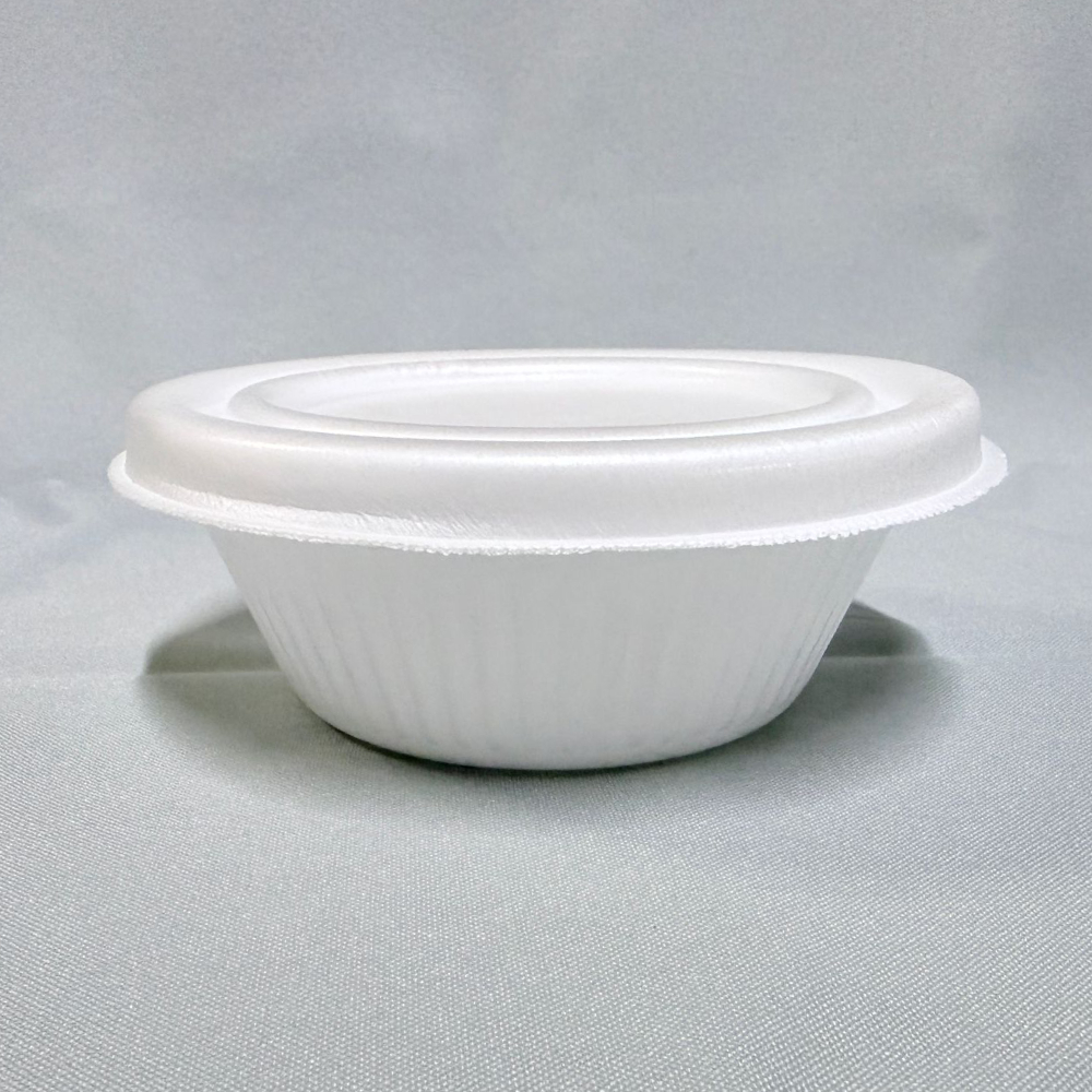 Pote térmico redondo y de perfil bajo fabricado en espuma blanca (EPS), con su respectiva tapa colocada, visto en ángulo desde arriba sobre un fondo claro.